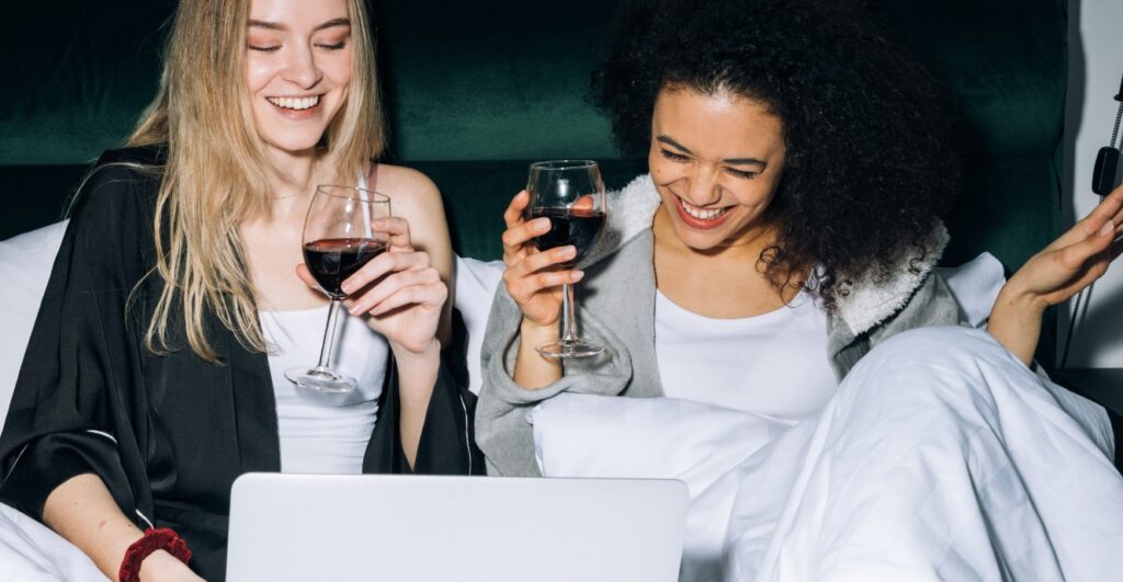 two girl laughing with wine over a movie